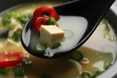Eating delicious miso soup with tofu from bowl, closeup