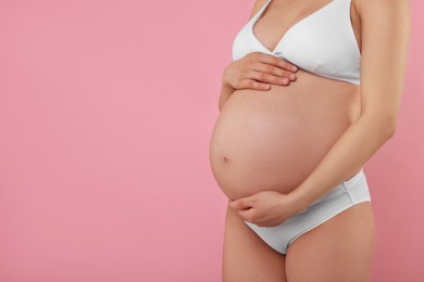 Photo of Pregnant woman in stylish comfortable underwear on pink background, closeup. Space for text