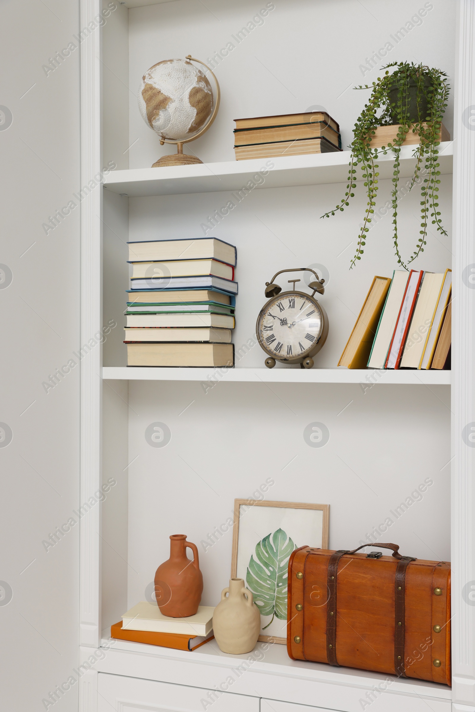 Photo of Books and different decorative elements on shelving unit indoors