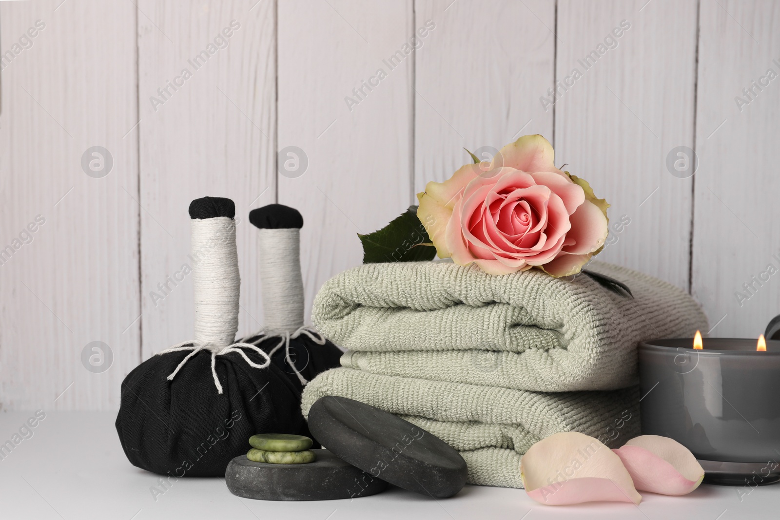 Photo of Composition with different spa products, rose and candle on white table against wooden background