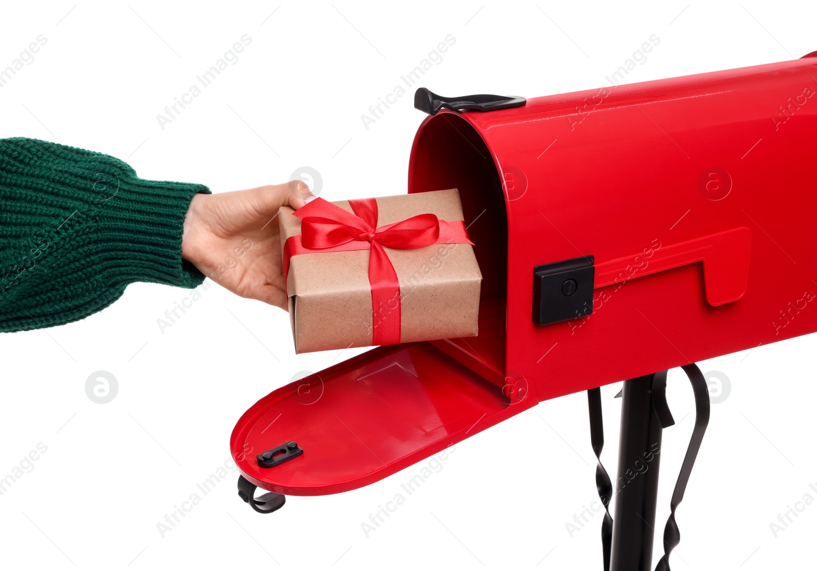 Photo of Woman putting Christmas gift into mailbox on white background, closeup. Sending present by mail