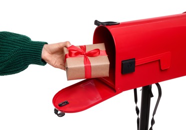 Photo of Woman putting Christmas gift into mailbox on white background, closeup. Sending present by mail