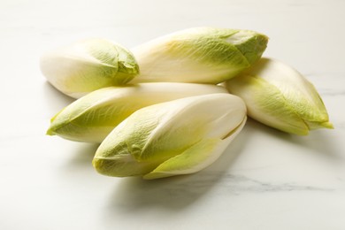 Photo of Raw ripe chicories on white marble table