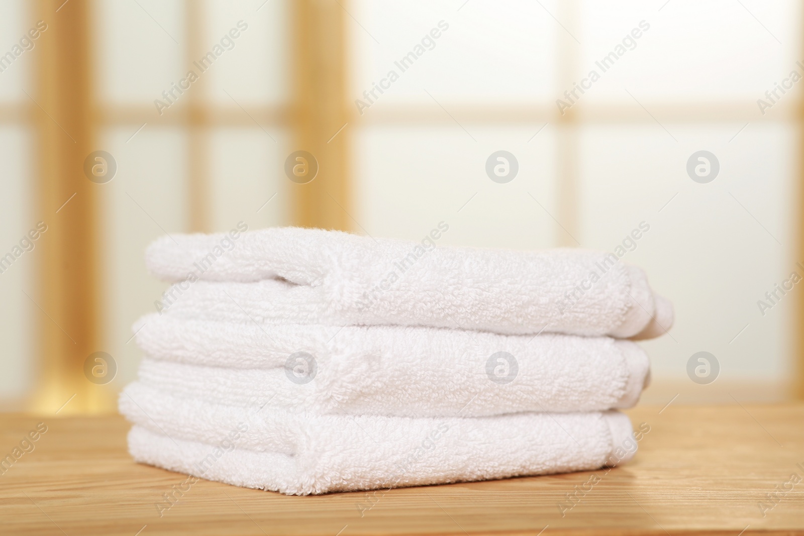 Photo of Soft folded terry towels on wooden table indoors