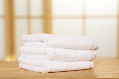 Photo of Soft folded terry towels on wooden table indoors