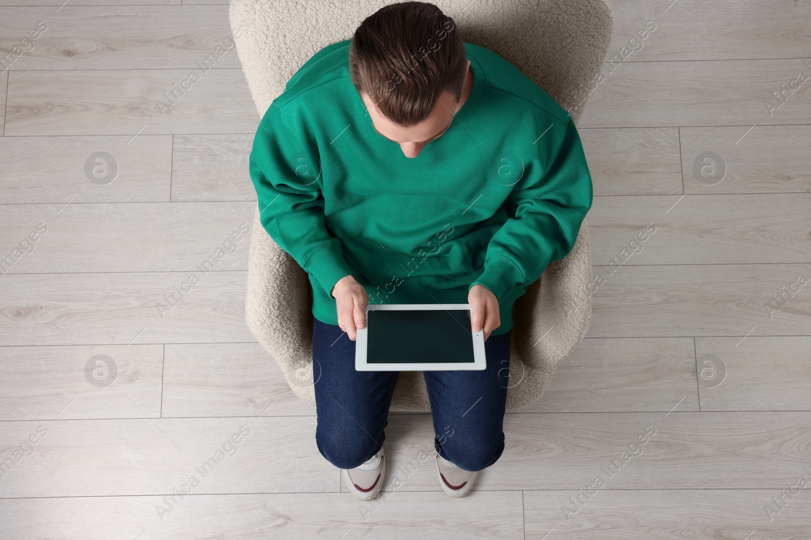 Photo of Man working with tablet in armchair, top view