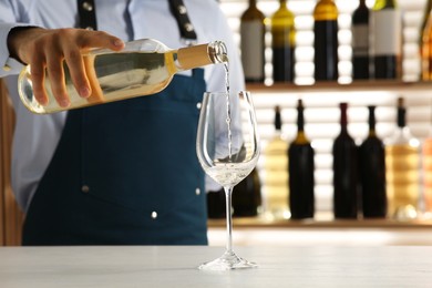 Photo of Bartender pouring wine into glass at counter in restaurant, closeup