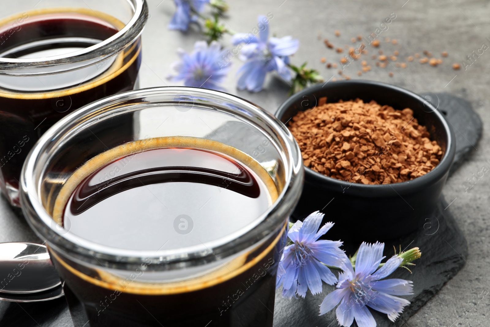Photo of Delicious chicory drink, granules and flowers on grey table, closeup