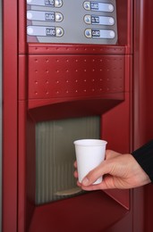 Image of Woman taking cup of beverage from coffee vending machine, closeup