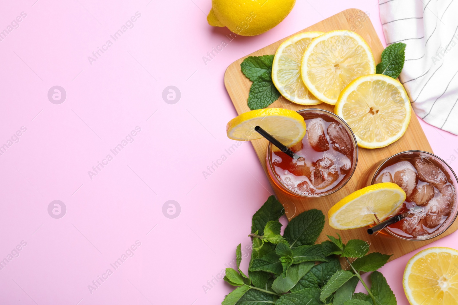 Photo of Delicious iced tea with lemon and mint on pink background, flat lay. Space for text