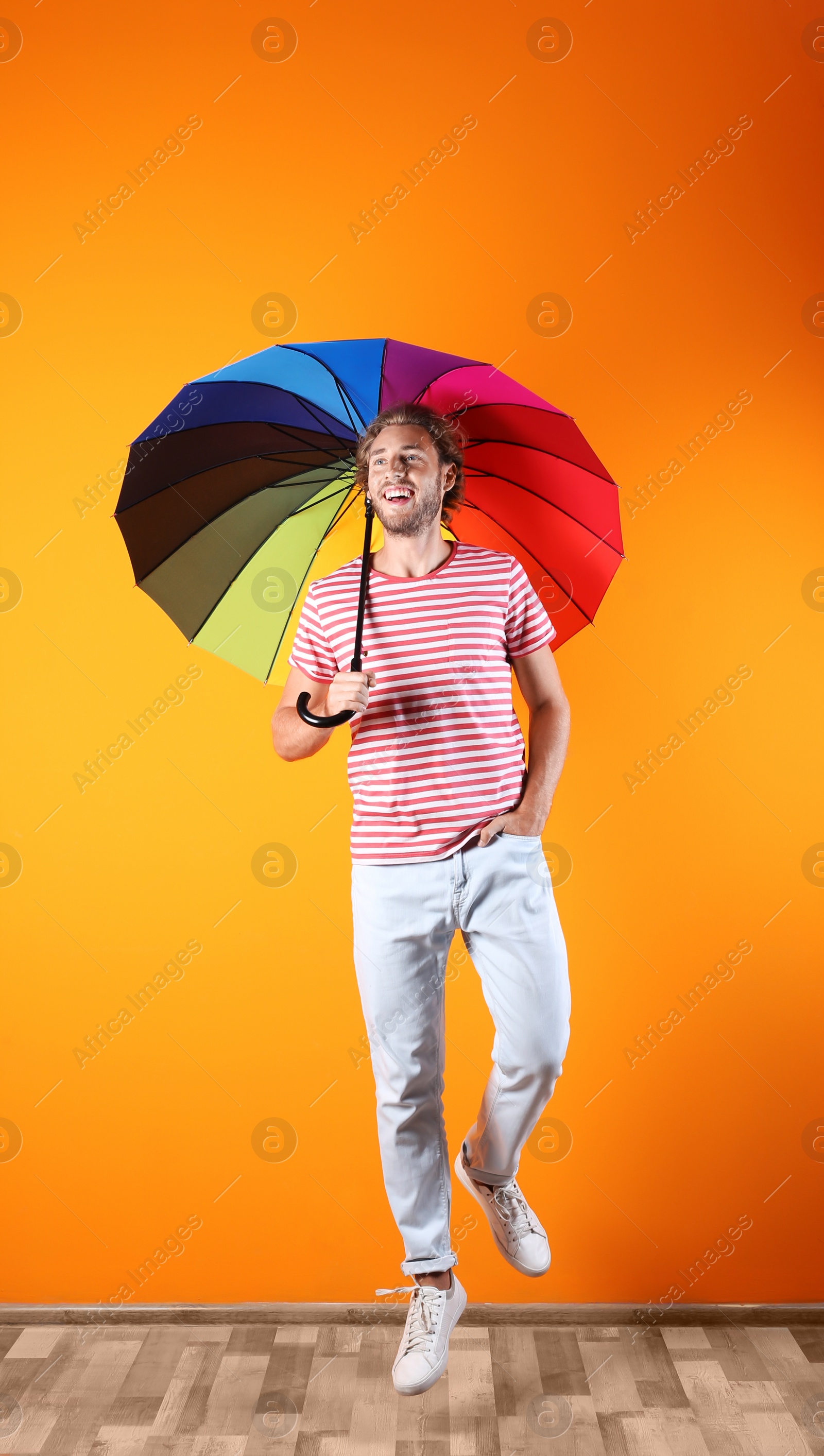 Photo of Man with rainbow umbrella near color wall