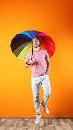 Man with rainbow umbrella near color wall