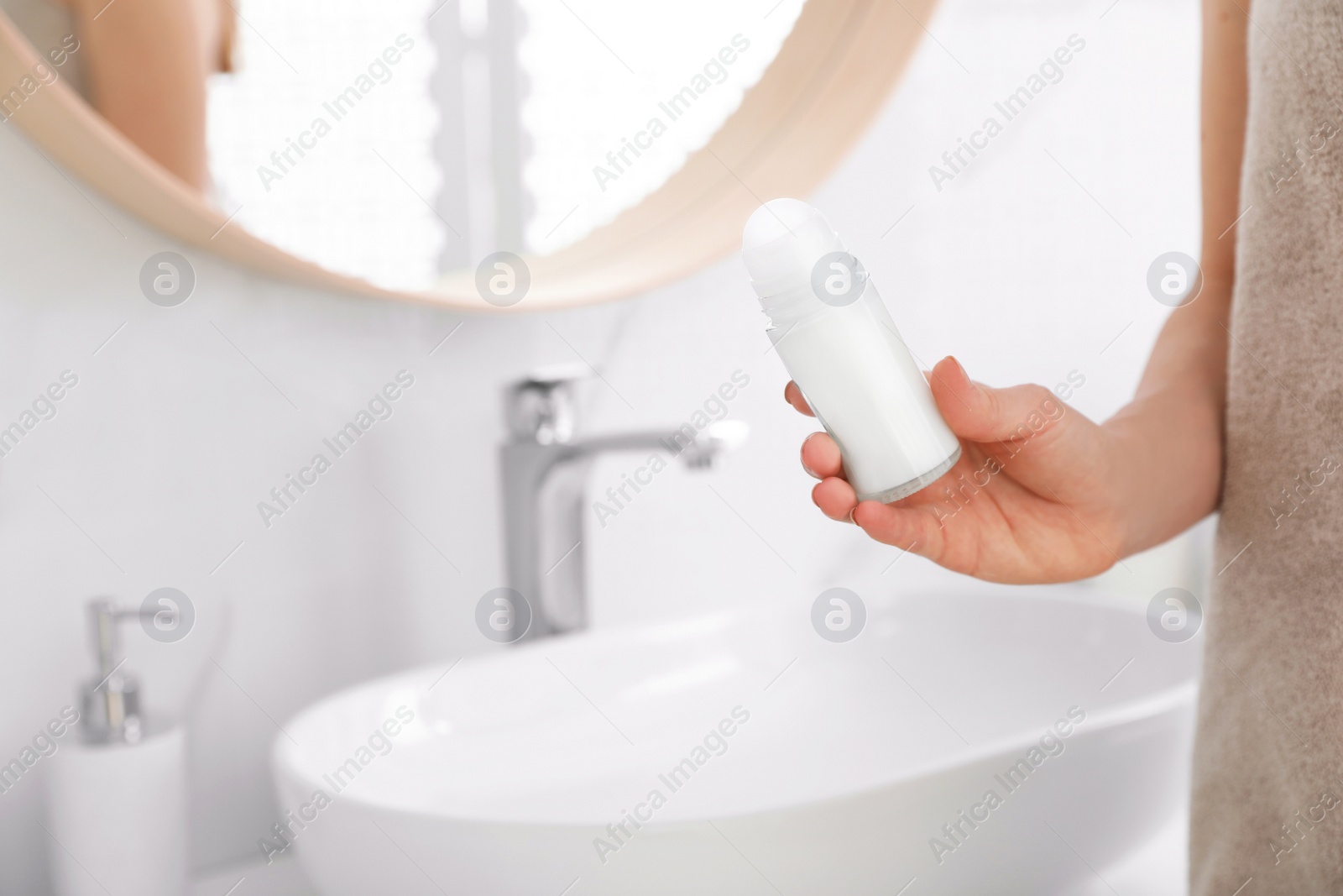 Photo of Young woman with roll on deodorant in bathroom, closeup view. Space for text