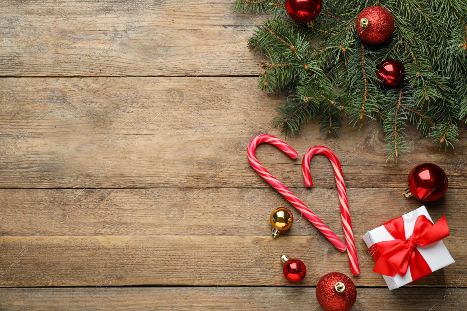 Photo of Flat lay composition with tasty candy canes and Christmas decor on wooden table, space for text