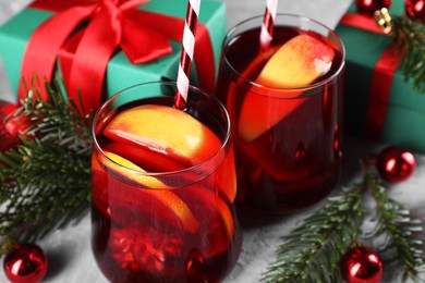 Delicious Sangria drink in glasses and Christmas decorations on grey table, closeup