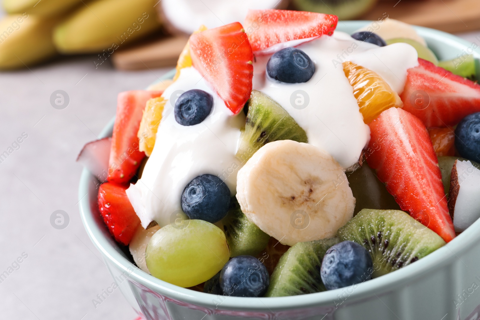 Photo of Delicious fruit salad with yogurt in bowl on table, closeup