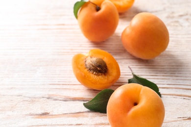 Photo of Delicious ripe apricots on white wooden background, closeup. Space for text