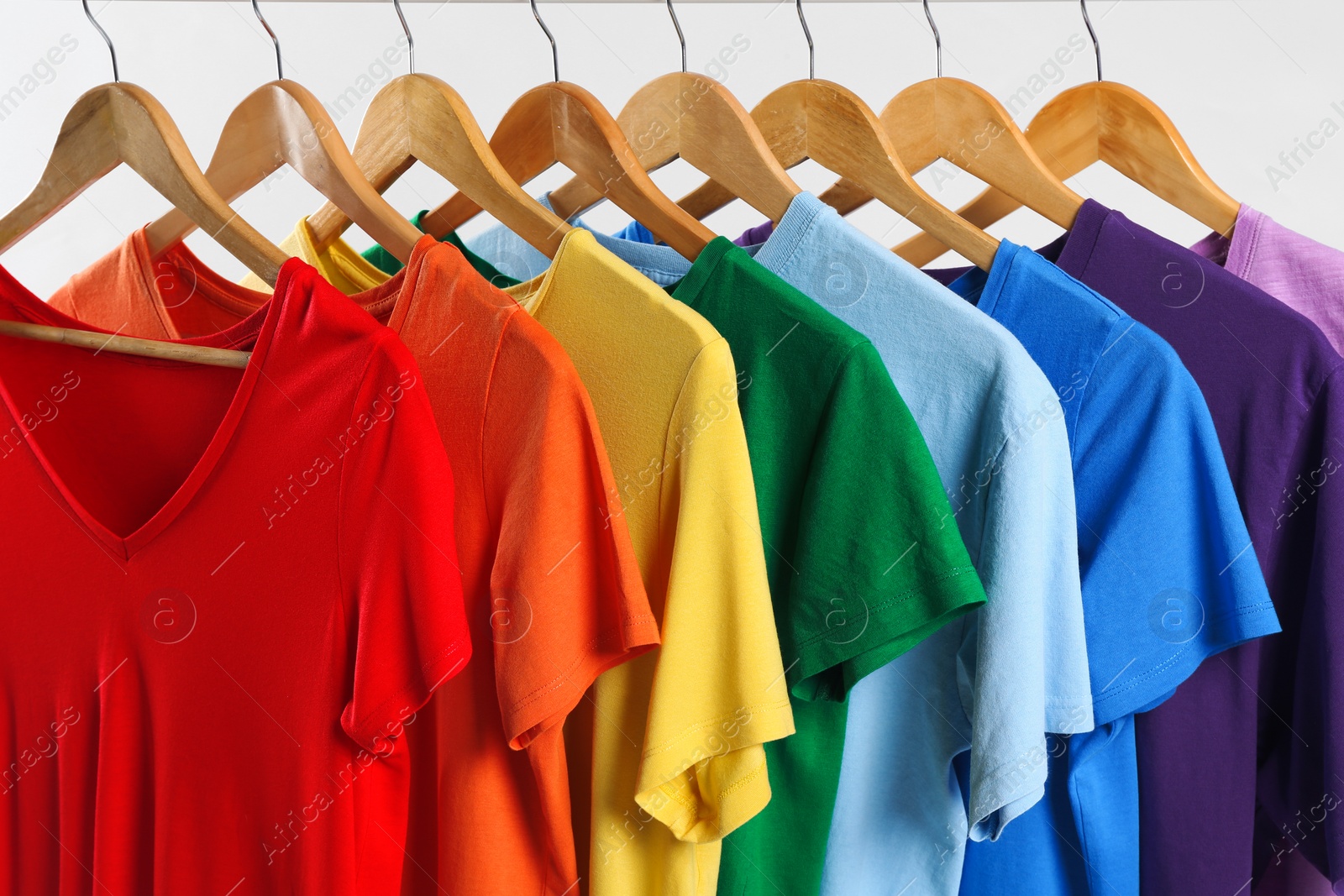 Photo of Colorful clothes on hangers against white background