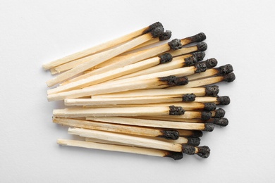 Heap of burnt matches on white background, top view