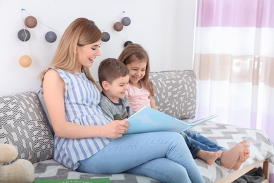 Nanny reading book to little children at home