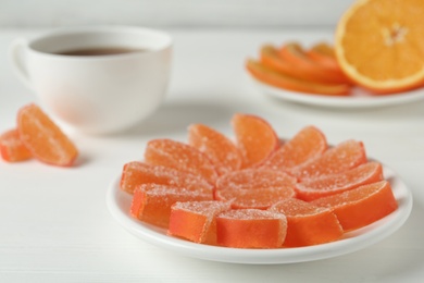 Tasty orange jelly candies on white table, closeup