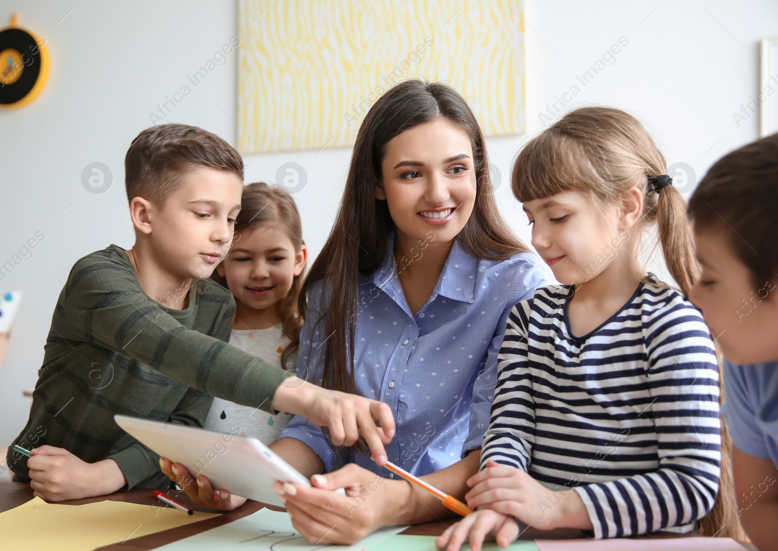 Photo of Cute little children with teacher in classroom at school