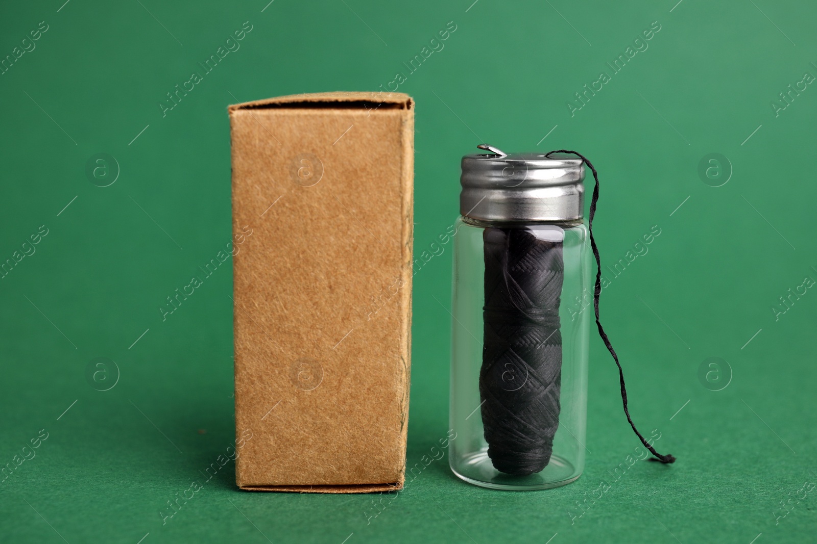 Photo of Biodegradable dental floss and cardboard package on dark green background