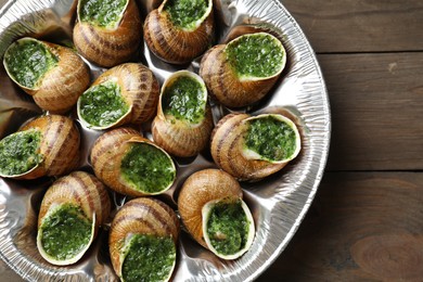 Photo of Delicious cooked snails on wooden table, top view
