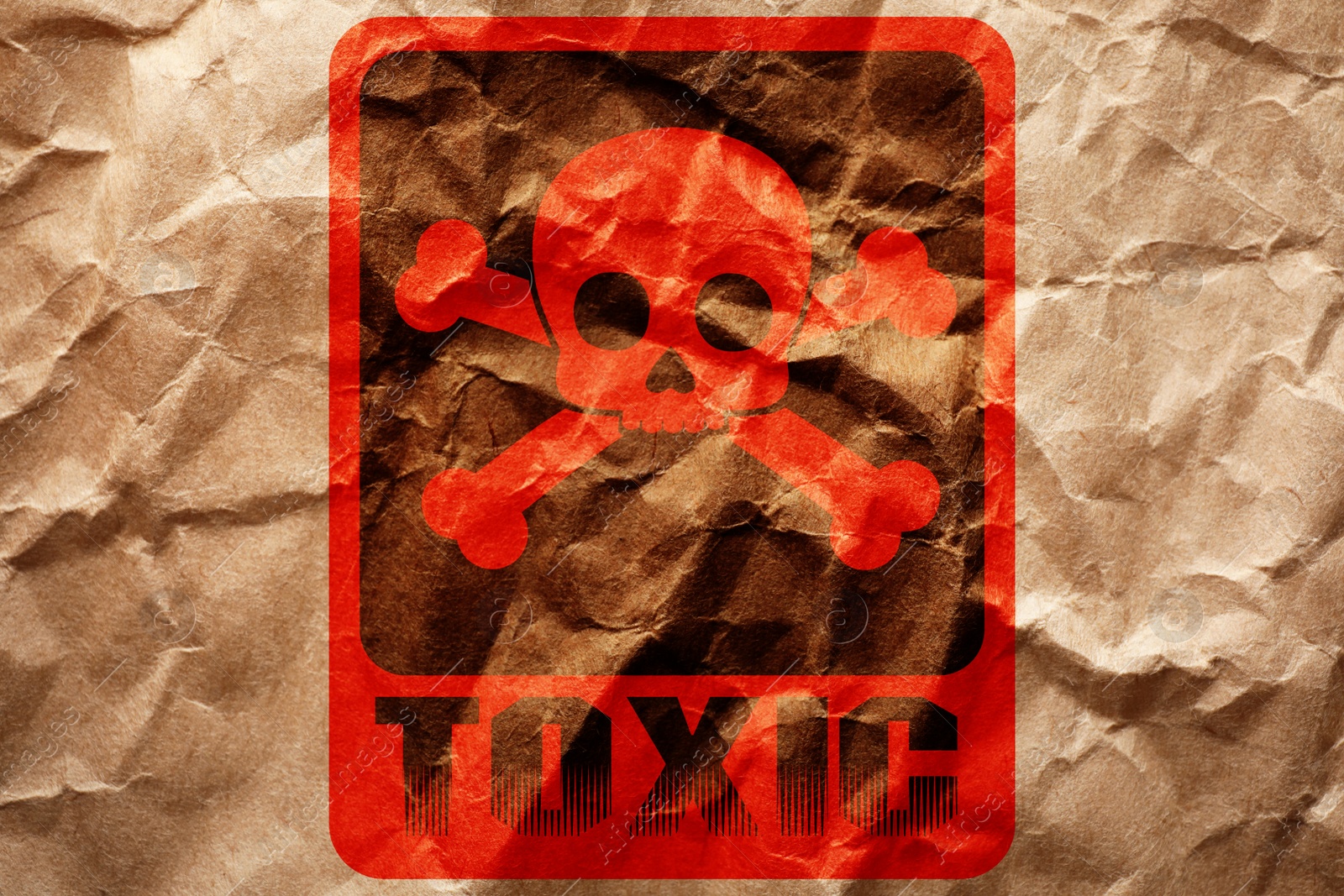 Image of Hazard warning sign (skull-and-crossbones symbol and word TOXIC) on crumpled kraft paper, top view