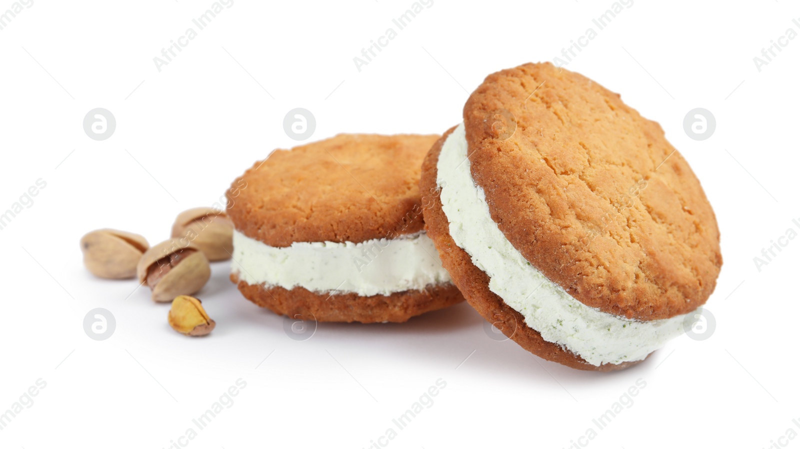 Photo of Sweet delicious ice cream cookie sandwiches and pistachios on white background