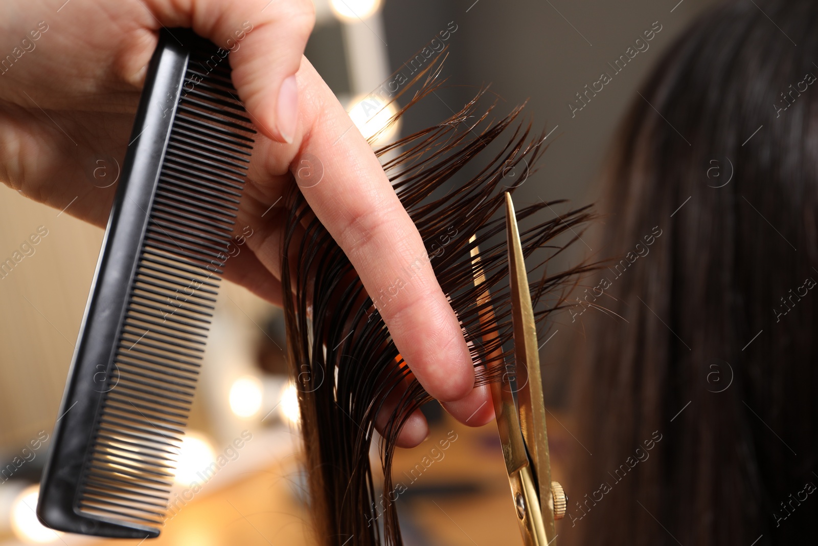 Photo of Hairdresser cutting client's hair with scissors in salon, closeup