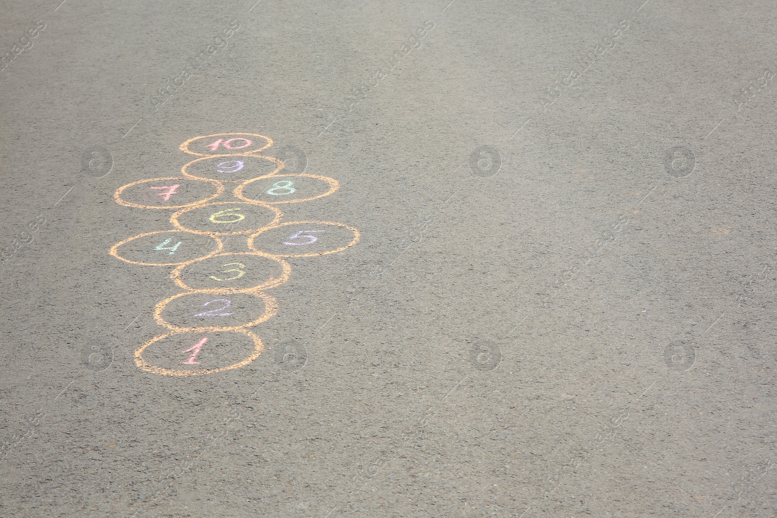 Photo of Hopscotch drawn with colorful chalk on asphalt outdoors, space for text