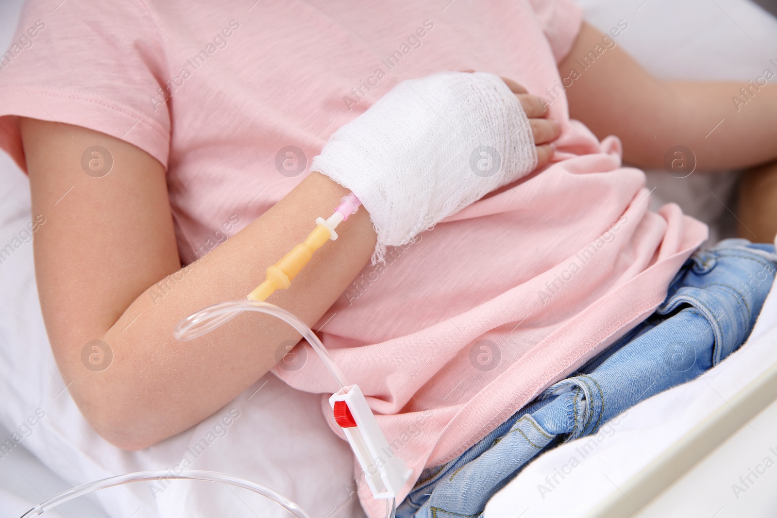 Photo of Little child with intravenous drip in hospital bed, closeup