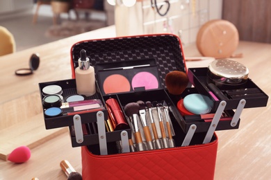 Beautician case with professional makeup products and tools on wooden dressing table