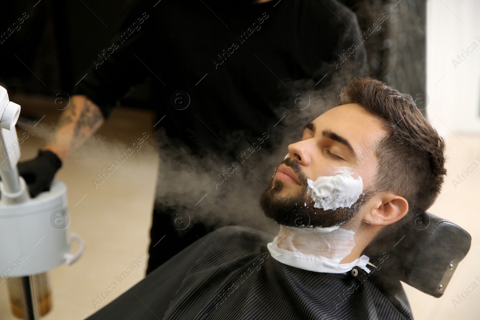 Photo of Hairdresser working with client at barbershop. Professional shaving service