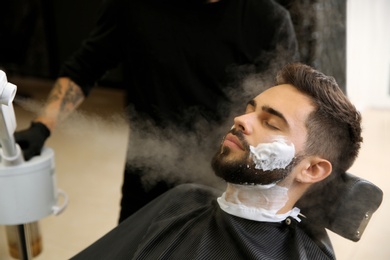 Photo of Hairdresser working with client at barbershop. Professional shaving service