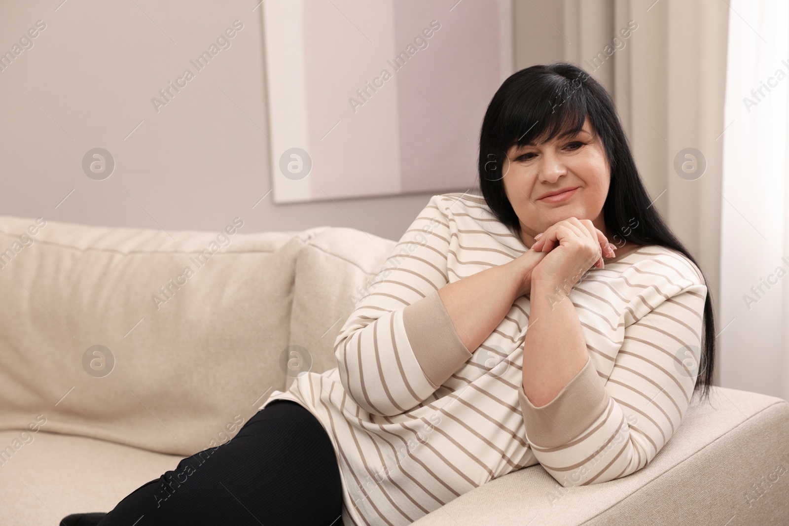 Photo of Beautiful overweight woman sitting on sofa at home