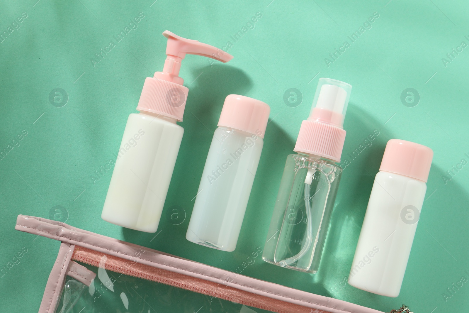 Photo of Cosmetic travel kit with plastic bag on turquoise background, top view