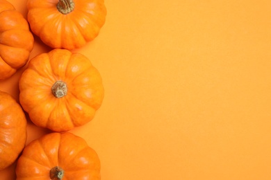 Photo of Fresh ripe pumpkins on orange background, flat lay. Space for text