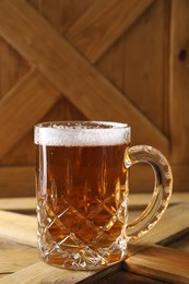 Photo of Mug with fresh beer on wooden crate