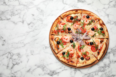 Photo of Tasty pizza with seafood on white marble table, top view. Space for text