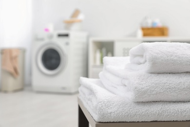 Stack of clean towels on table in bathroom.  Space for text