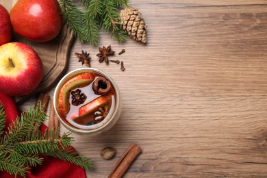 Photo of Hot mulled cider, ingredients and fir branches on wooden table, flat lay. Space for text