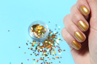Photo of Woman showing manicured hand with golden nail polish over color background, closeup. Space for text