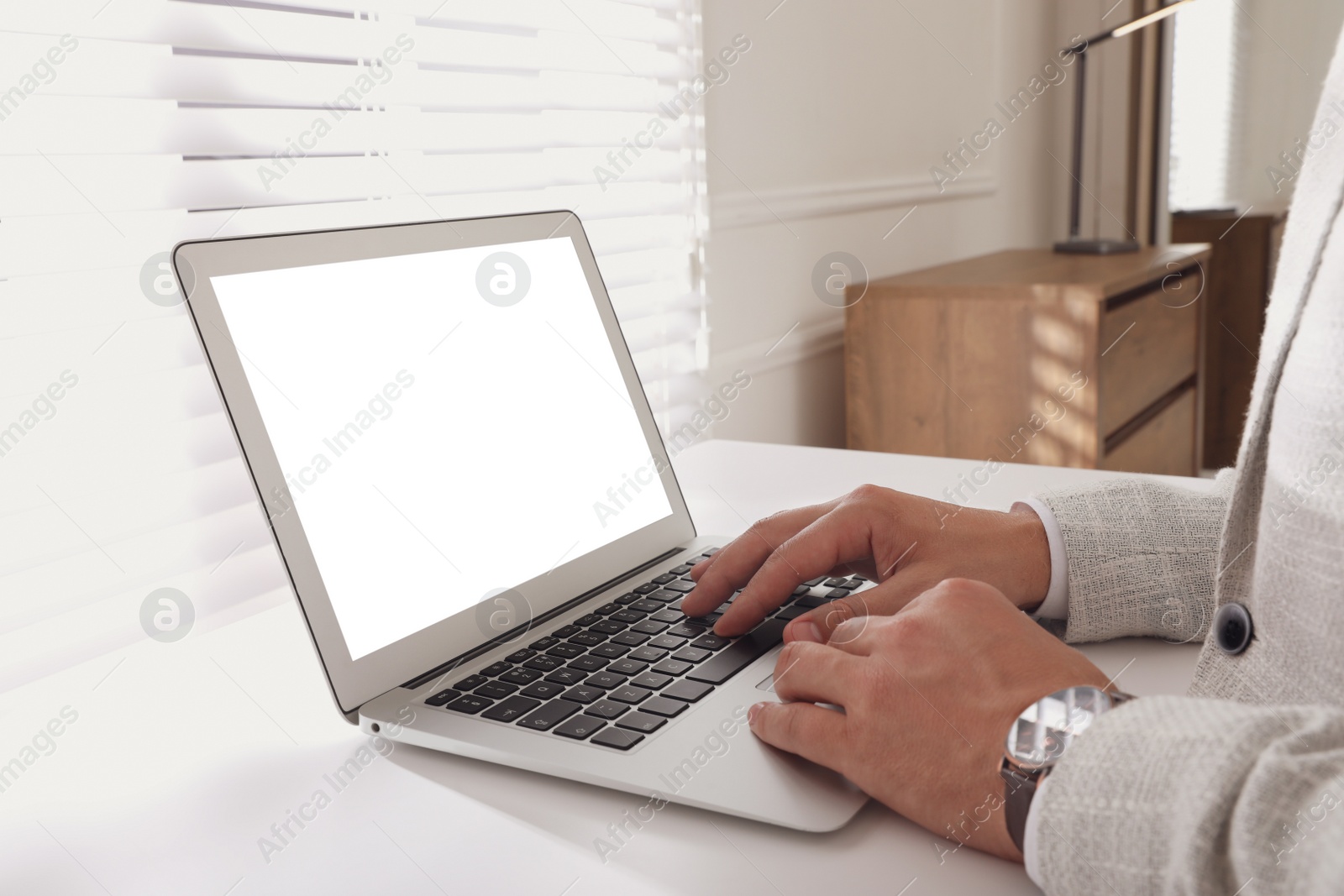 Photo of Businessman with modern laptop at white table indoors, closeup. Space for design