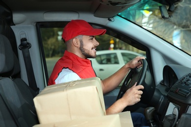 Photo of Young courier driving delivery van with parcels
