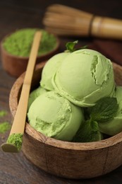Tasty matcha ice cream in bowl and bamboo spoon with powder on table, closeup