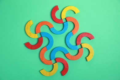 Photo of Colorful wooden pieces of play set on green background, flat lay. Educational toy for motor skills development
