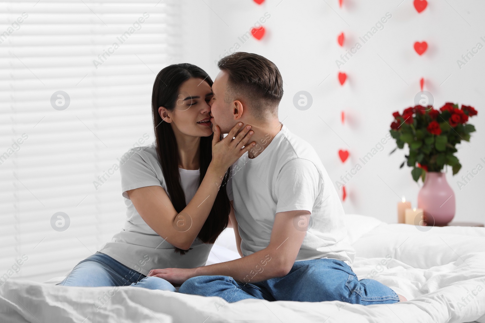 Photo of Lovely couple kissing on bed indoors. Valentine's day celebration