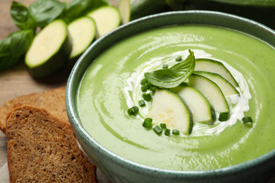 Photo of Tasty homemade zucchini cream soup in bowl on table, closeup